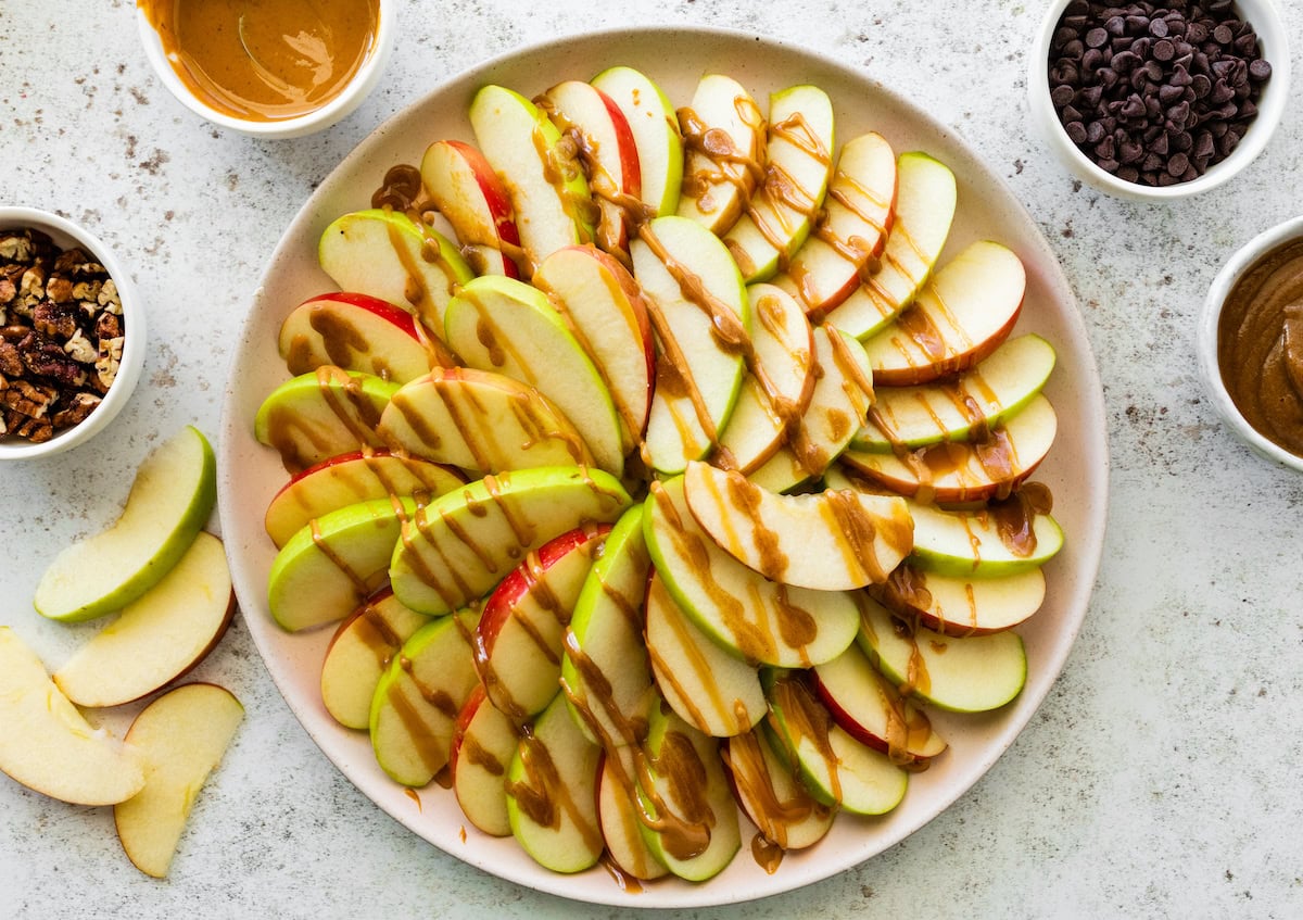 A large plate of apple slices topped with a date caramel drizzle.