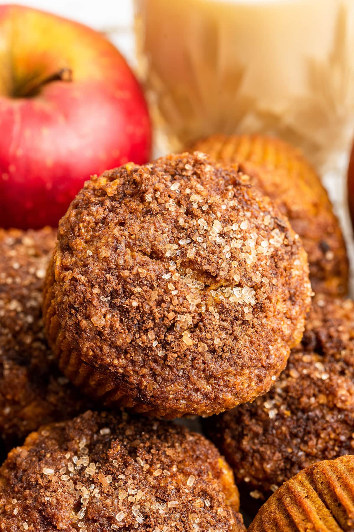 An apple muffin resting atop of multiple other apple muffins.