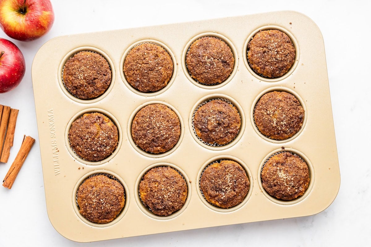 Apple muffins in a muffin tin after being baked in the oven.
