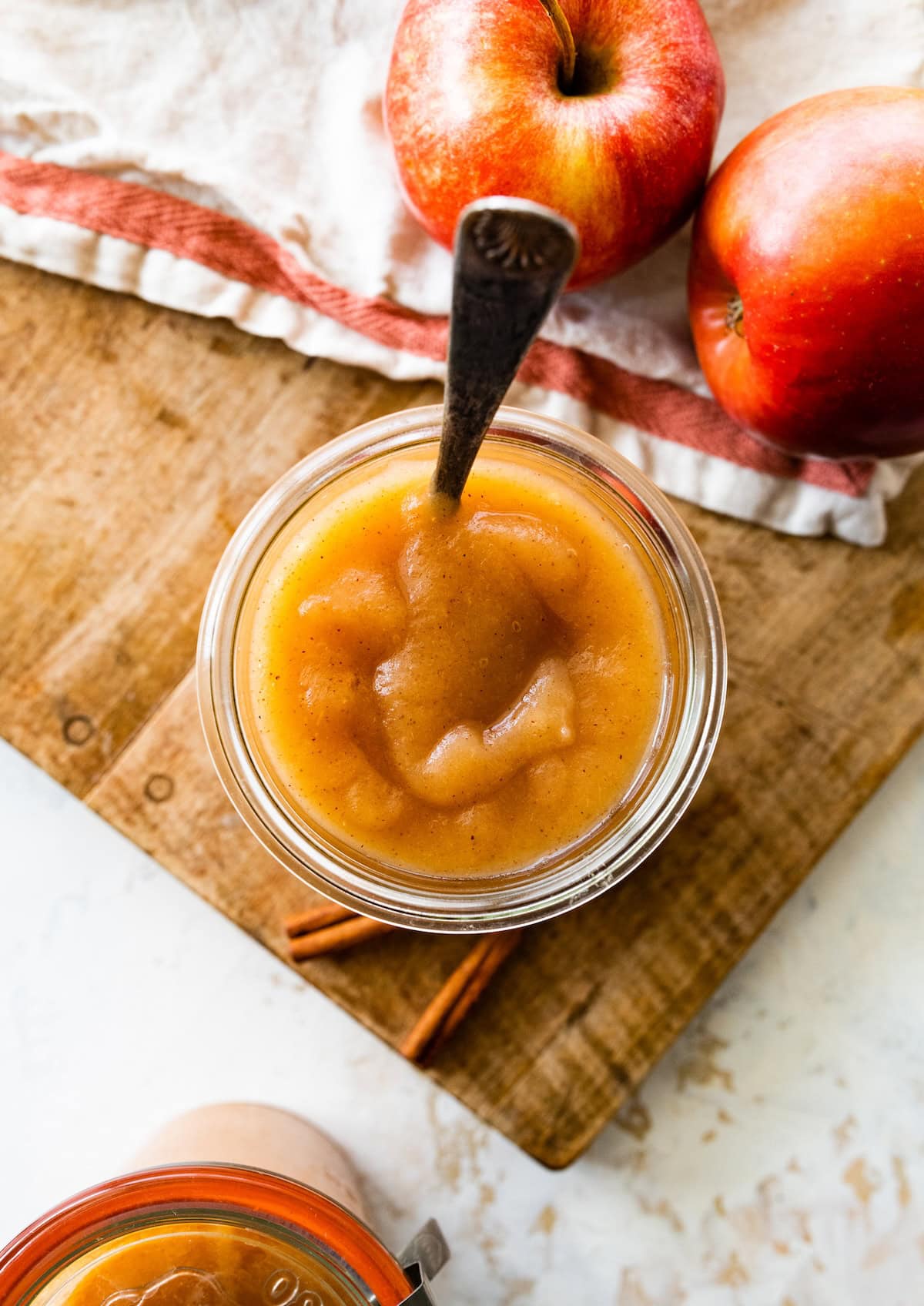 Homemade applesauce in a glass jar with a metal spoon.