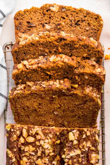 Four slices of pumpkin banana bread lean against one another on a cooling rack.