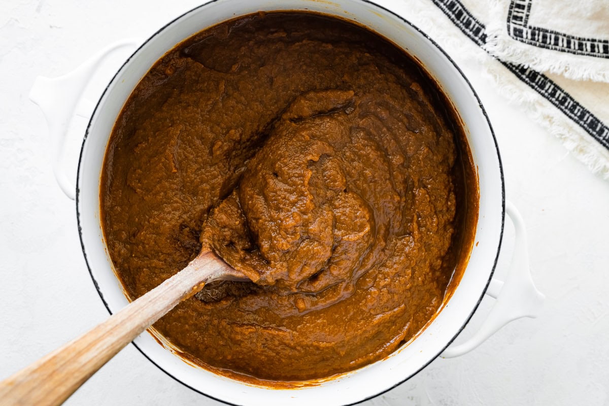 A large pot of pumpkin butter with a wooden serving spoon.