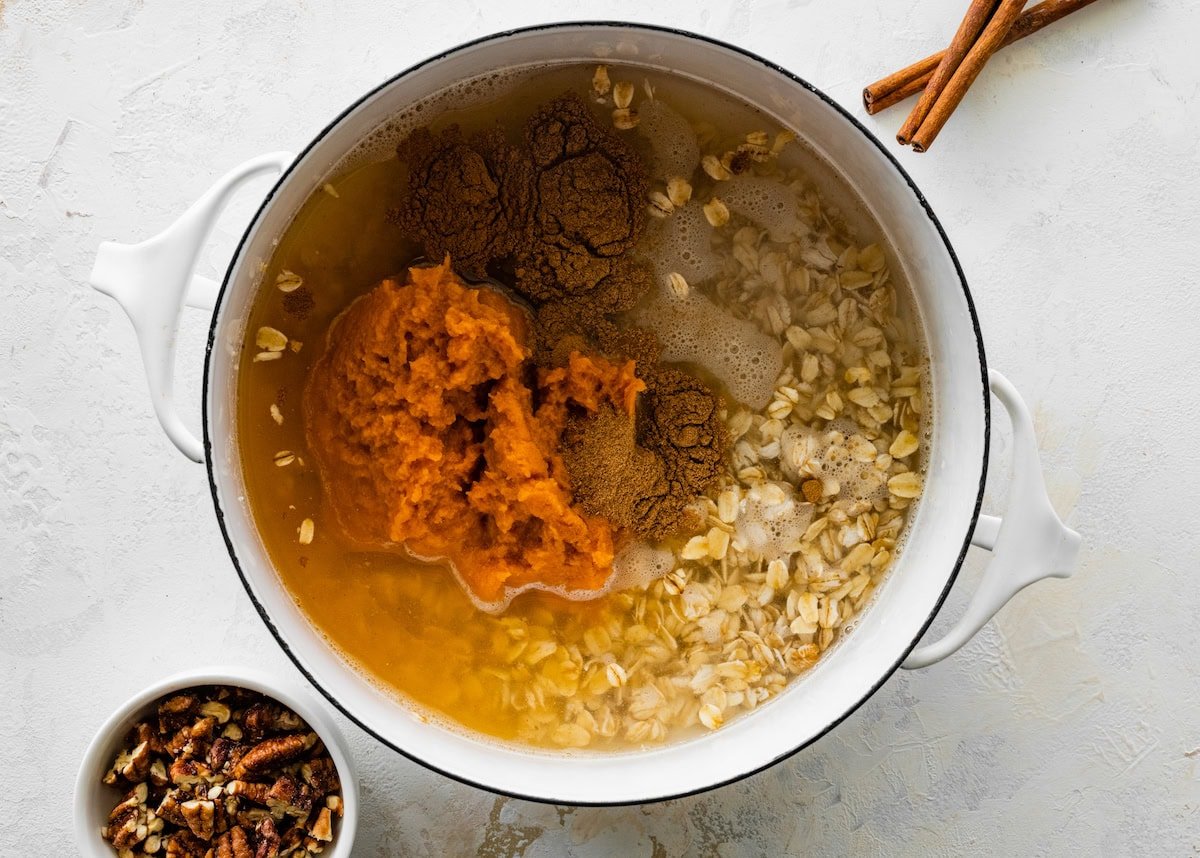 A saucepan with the pumpkin oatmeal ingredients in it before cooking: oats, pumpkin, spices and water.