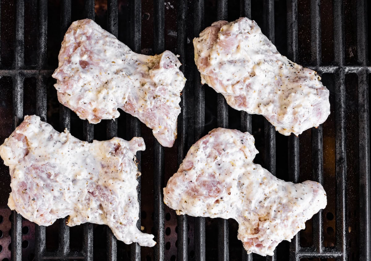 Four yogurt marinated chicken thighs on a grill.