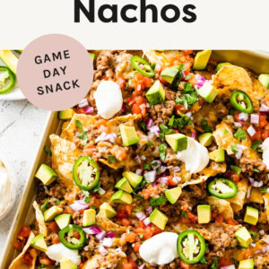 Nachos on a sheet pan topped with ground turkey refried bean mixture, cheese, tomatoes, avocado and jalapeños .