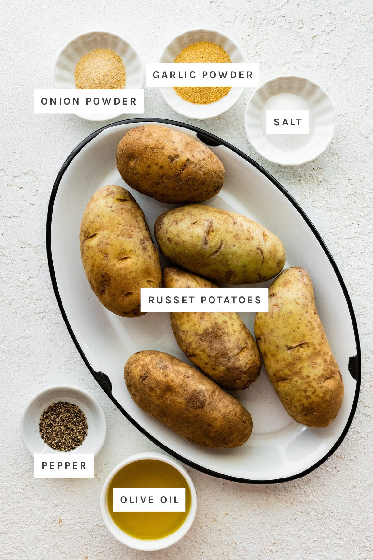 Ingredients measured out to make Roasted Potatoes: onion powder, garlic powder, salt, russet potatoes, pepper and olive oil.