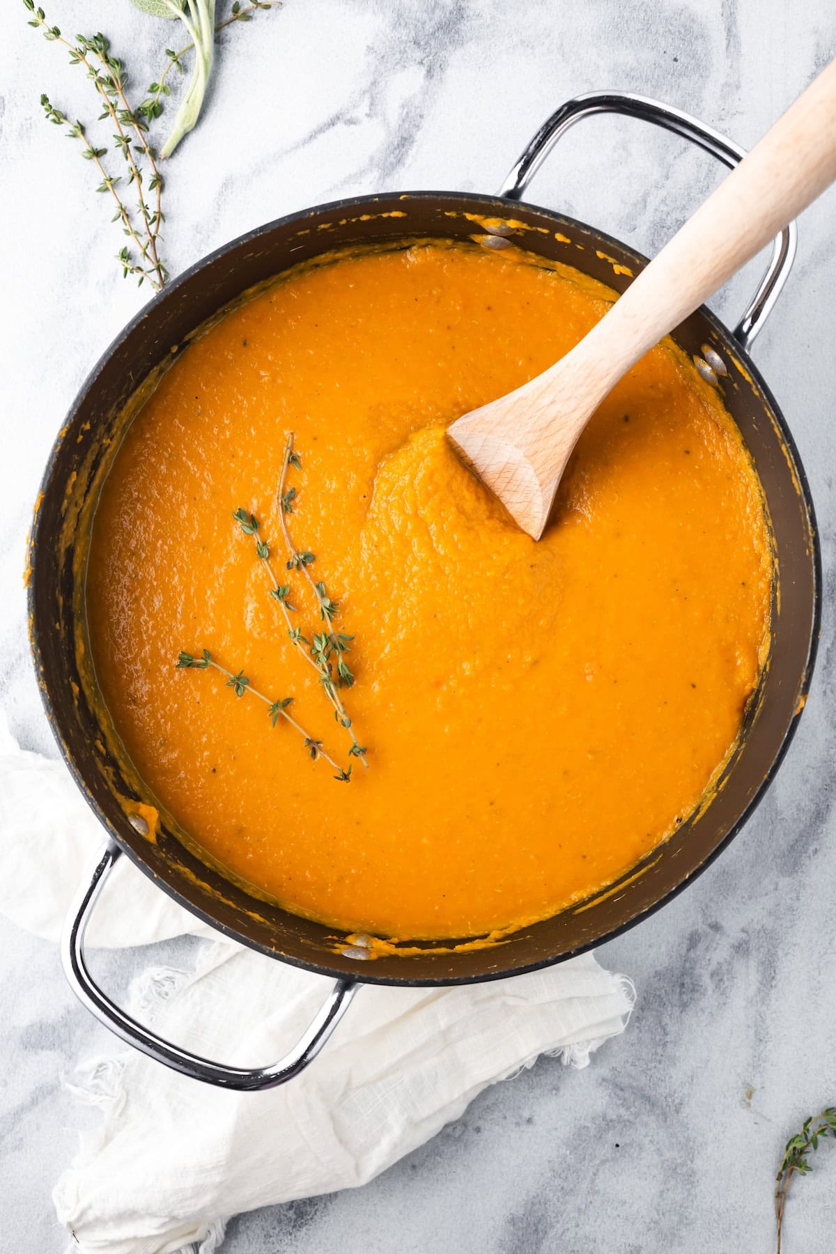 A large pot of carrot parsnip soup with a wooden serving spoon.