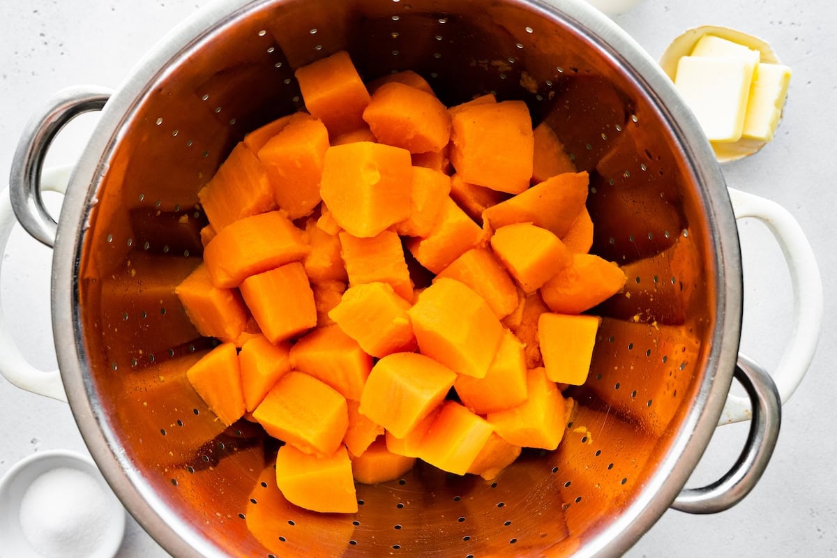 Cooked sweet potato chunks in a metal colander.