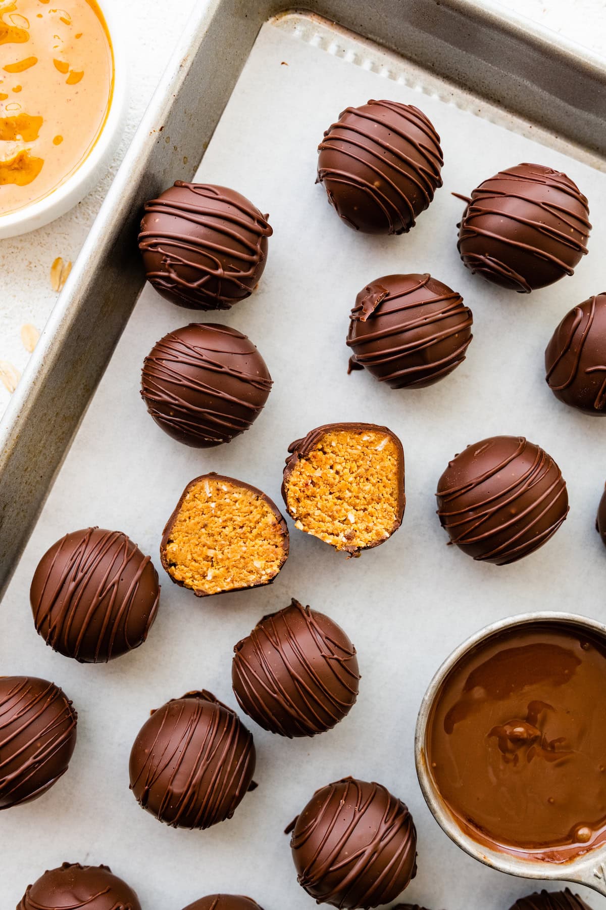 Chocolate covered peanut butter balls in a tray with one ball being split open.