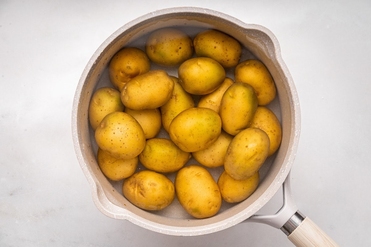 Multiple potatoes in a large pot of water.