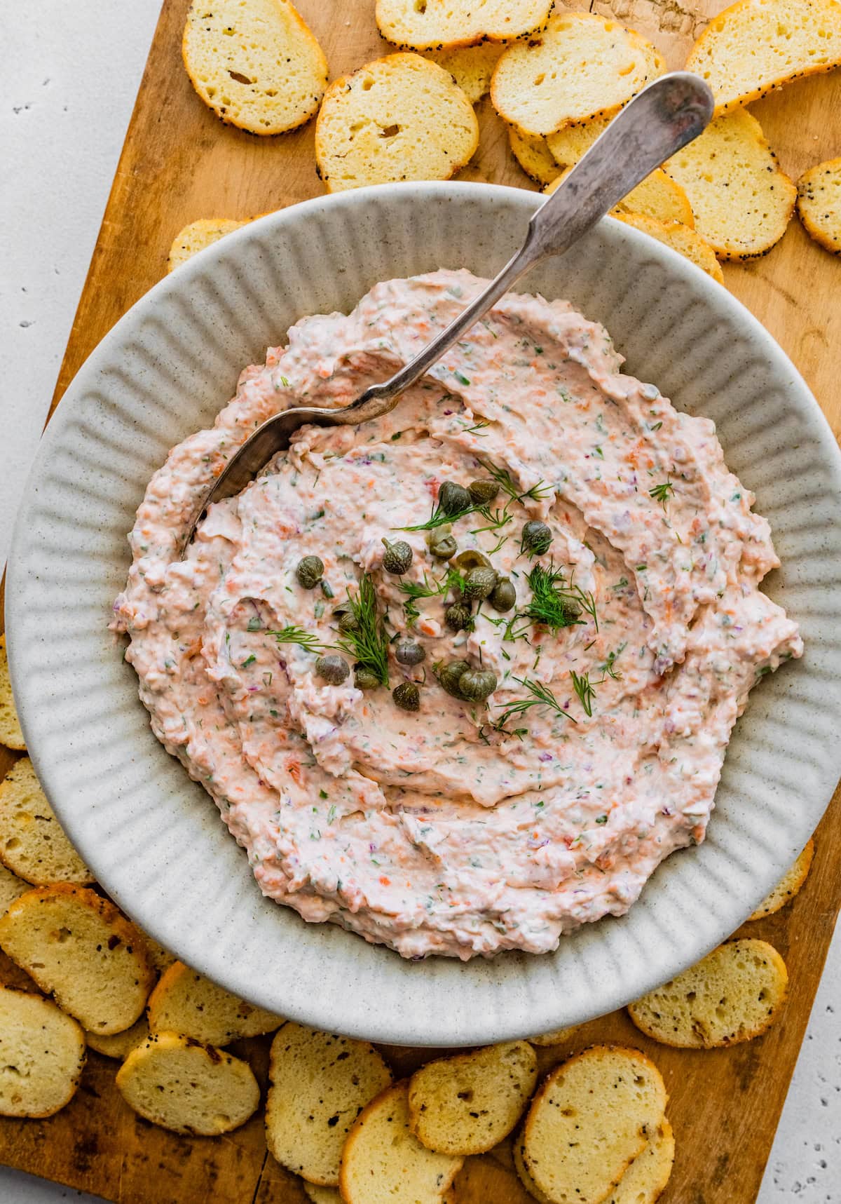 Smoked salmon dip in a bowl garnished with fresh dill and capers.