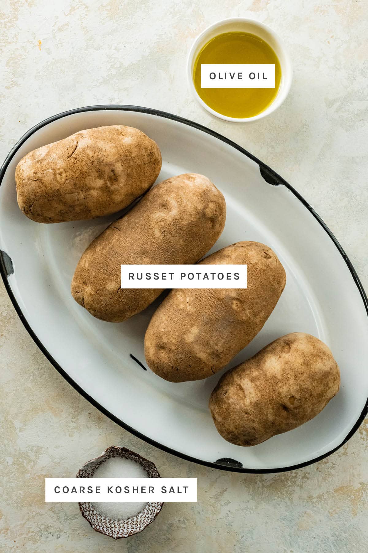 Ingredients measured out to make Oven Baked Potatoes: olive oil, russet potatoes and coarse kosher salt.
