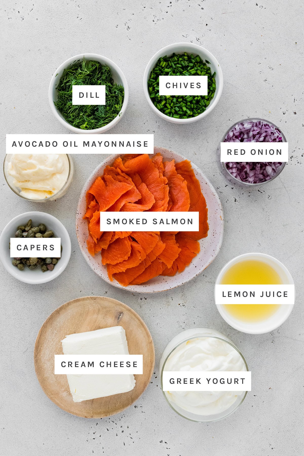Ingredients measured out to make Smoked Salmon Dip: dill, chives, avocado oil mayonnaise, red onion, smoked salmon, capers, cream cheese, Greek yogurt and lemon juice.