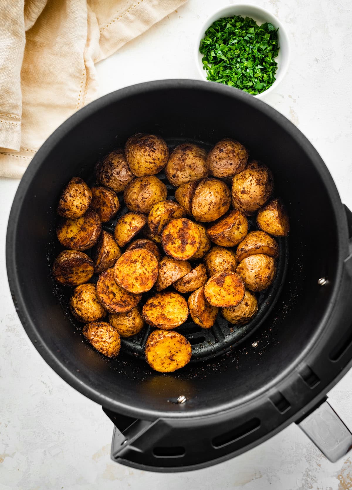 Crispy potatoes in an air fryer basket.