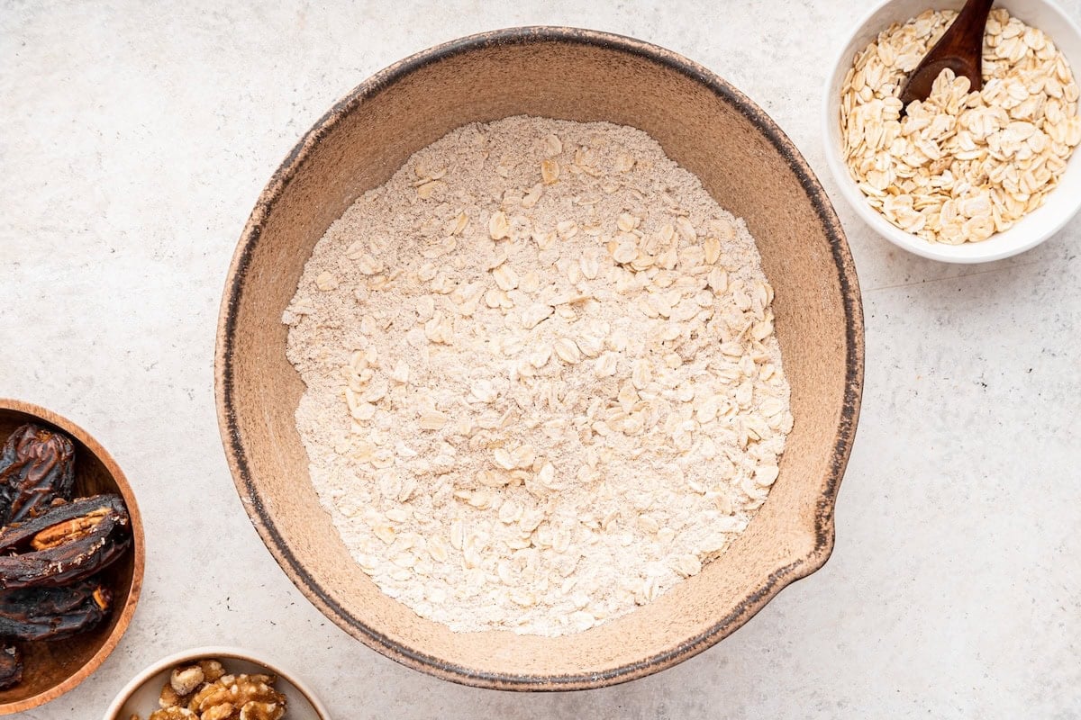 The dry ingredients for the oatmeal date cookies mixed together in a ceramic bowl.