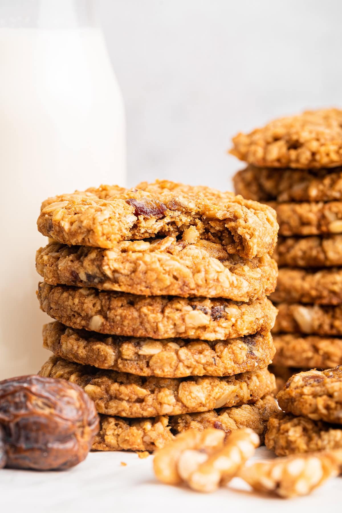 A stack of six oatmeal date cookies. The top cookie has a bite taken out of it.