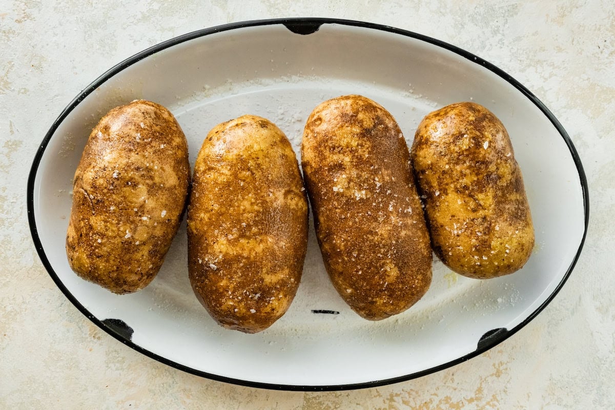 Four potatoes in a large pot covered with oil and salt.