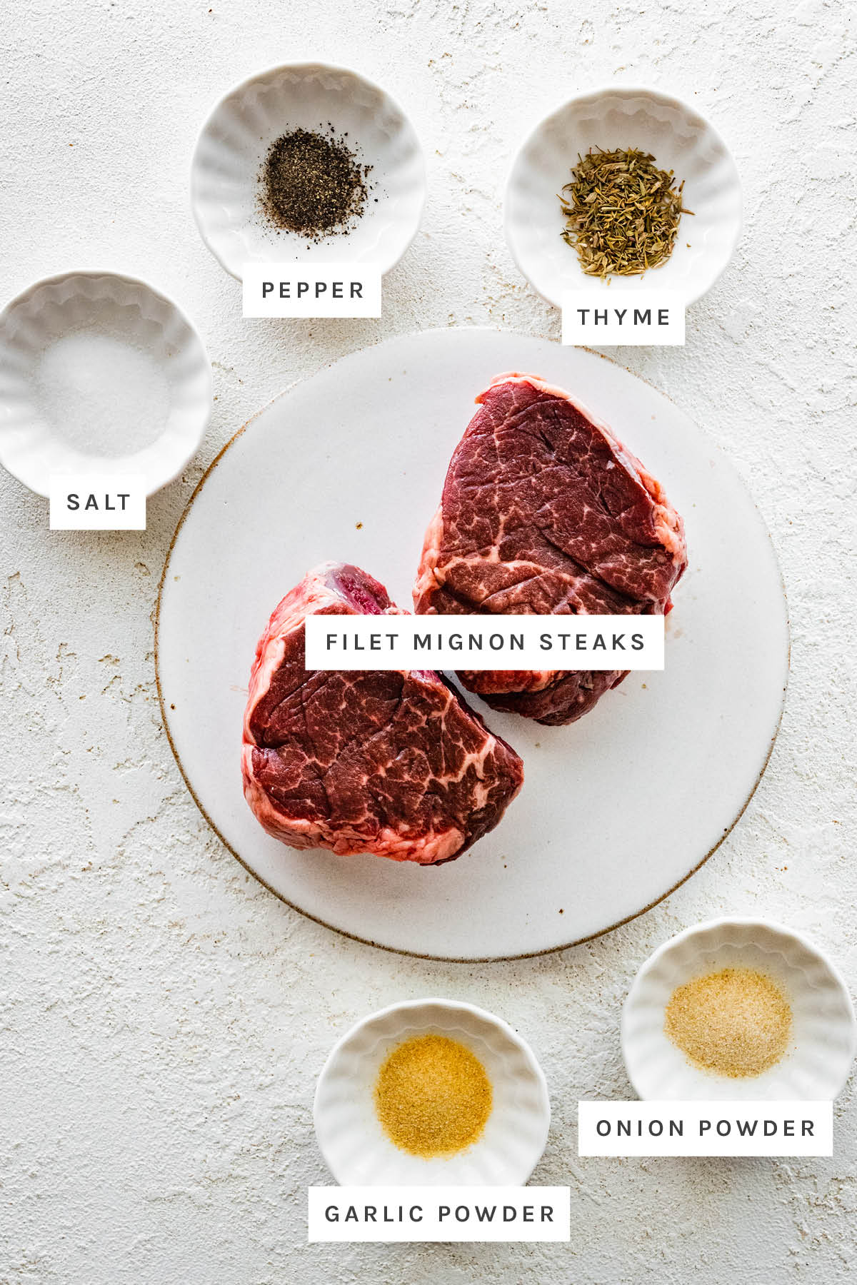 Ingredients measured out to make Air Fryer Filet Mignon: salt, pepper, thyme, filet mignon steaks, garlic powder and onion powder.