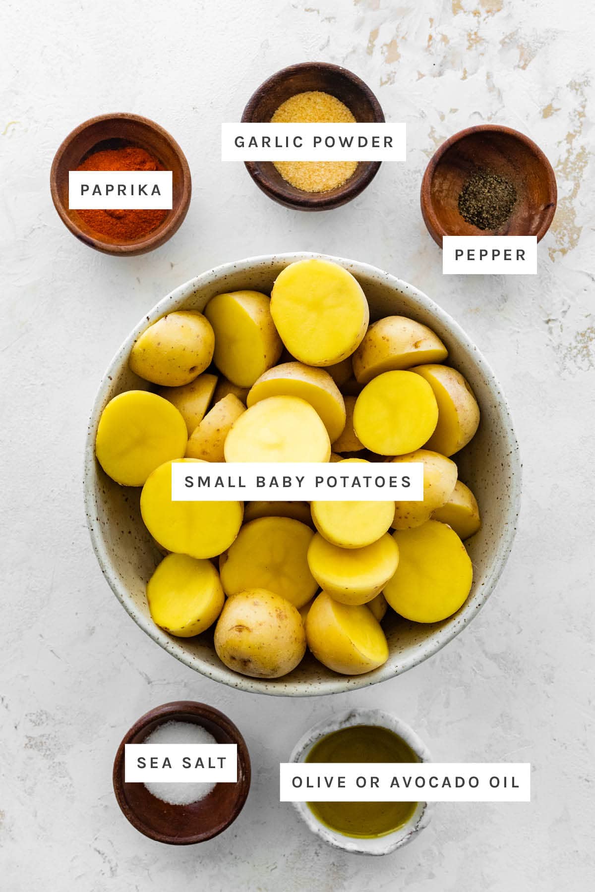 Ingredients measured out to make Air Fryer Potatoes: paprika, garlic powder, pepper, small baby potatoes, sea salt and olive oil.