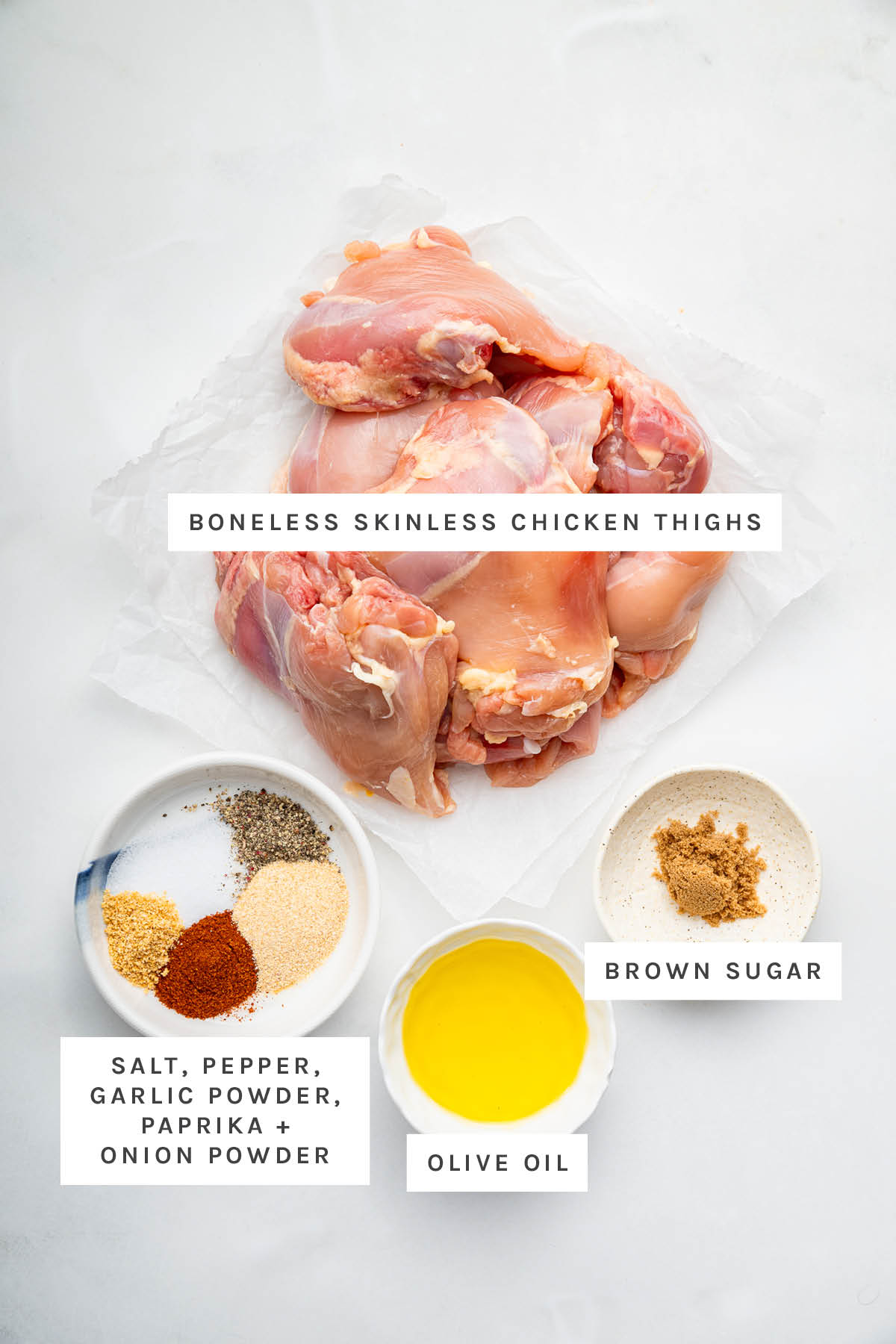 Ingredients measured out to make Baked Boneless Skinless Chicken Thighs: Boneless Skinless Chicken Thighs, salt, pepper, garlic powder, paprika, onion powder, olive oil and brown sugar.