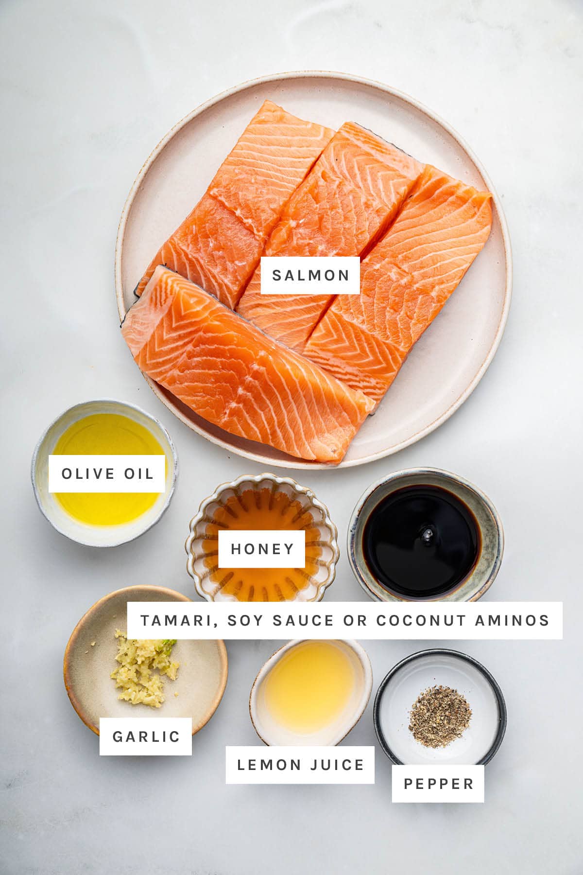 Ingredients measured out to make Honey Glazed Salmon: salmon, olive oil, honey, tamari, garlic, lemon juice and pepper.