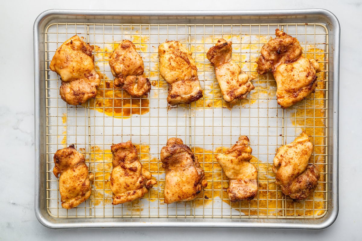 Baked boneless chicken thighs on a metal rack on a baking tray.