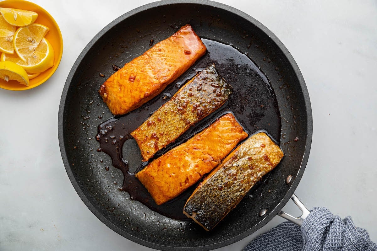 Four honey glazed salmons in a skillet.