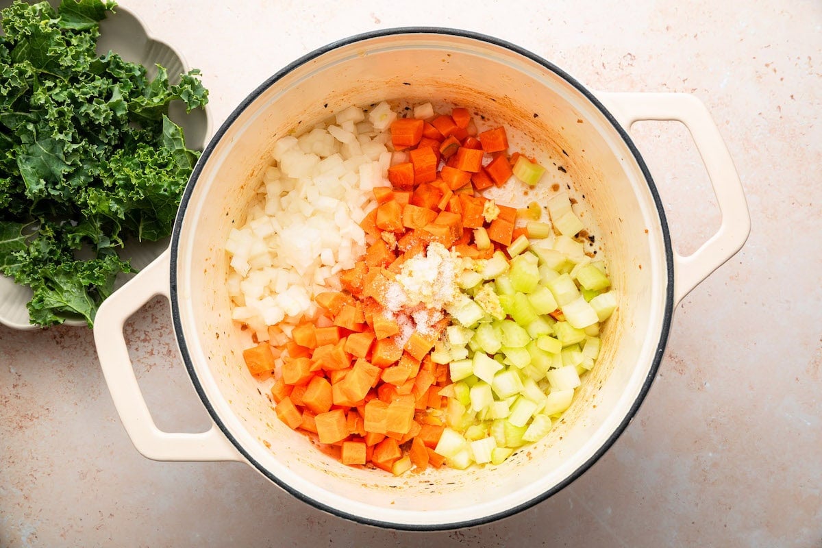 Carrots, celery, onions and garlic sautéing in a dutch oven pot for the sausage and kale soup.