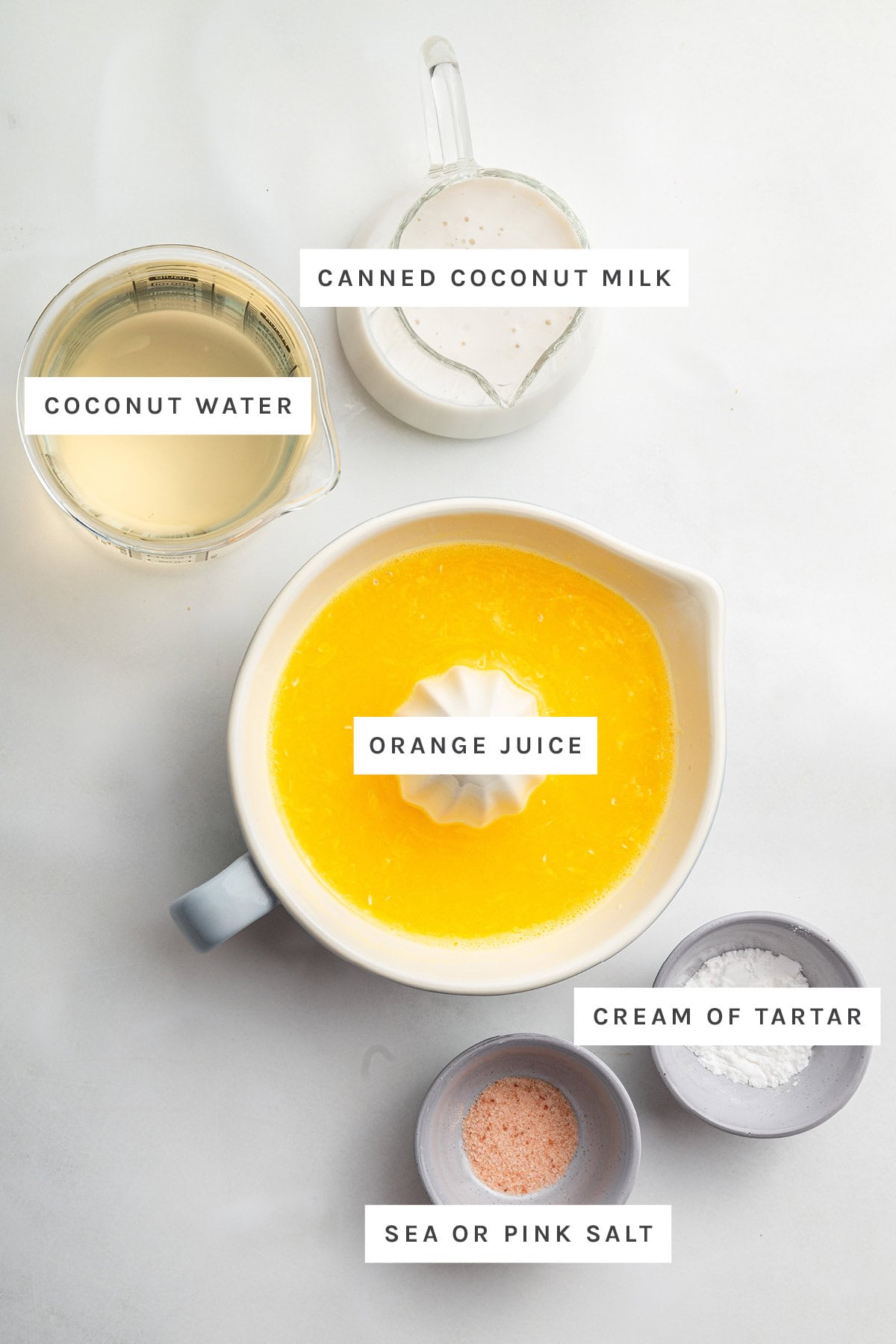 Ingredients measured out to make Adrenal Cocktail: coconut water, coconut milk, orange juice, pink salt and cream of tartar.