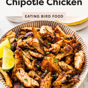 Chopped Chipotle Chicken thighs in a bowl with lime wedges.