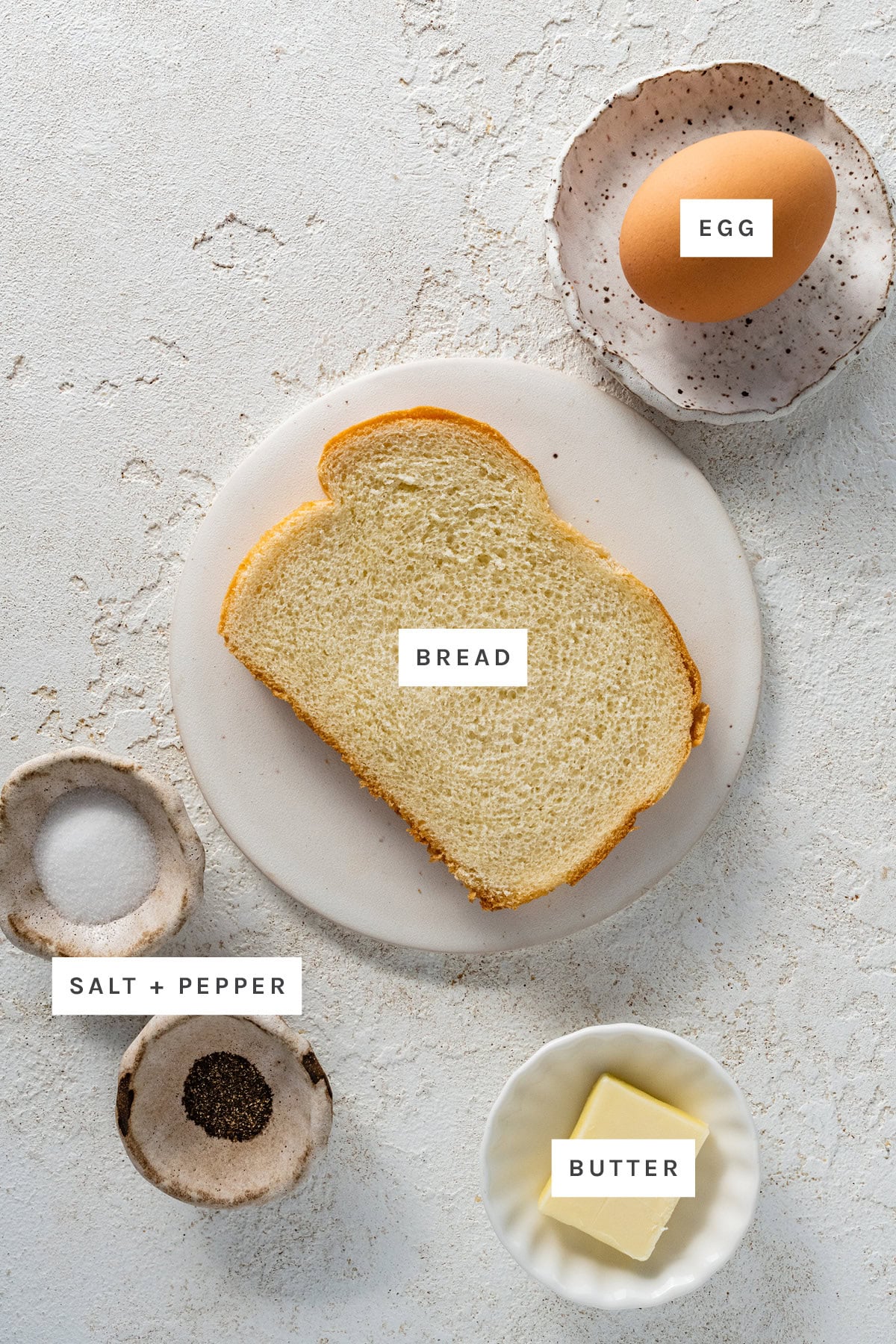 Ingredients measured out to make Egg in the Hole: egg, bread, salt, pepper and butter.