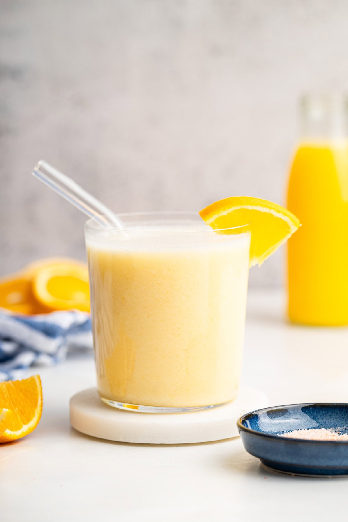 An adrenal cocktail in a glass with a clear straw in it. An orange slice is on the edge of the glass.