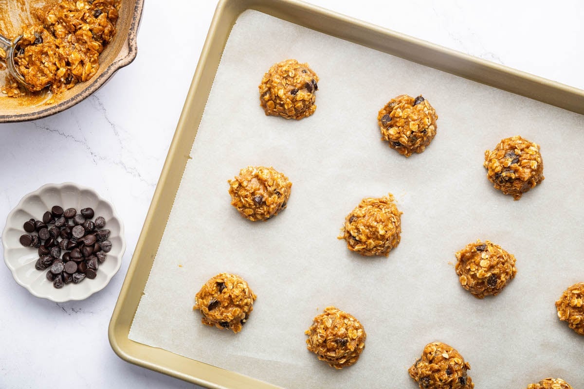 Small portions of peanut butter oatmeal cookie dough spread out on a baking tray before being baked.