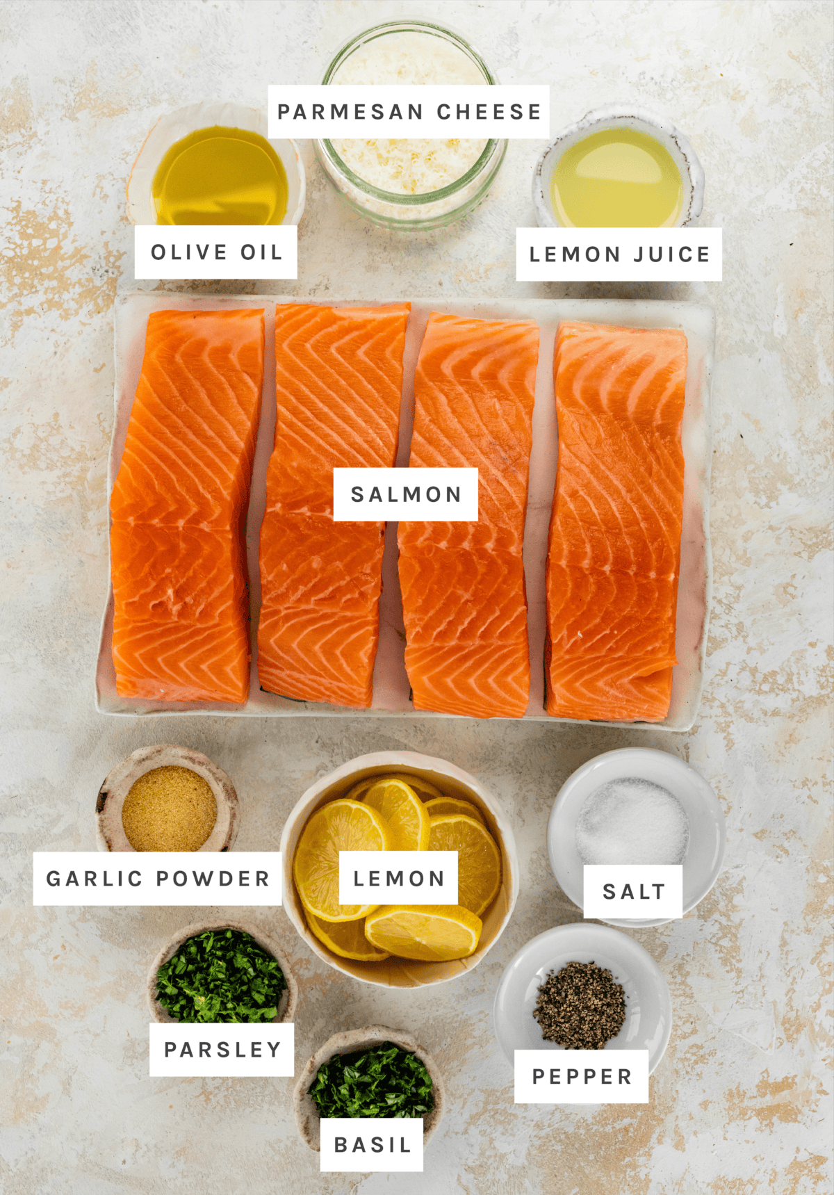 Ingredients measured out to make Parmesan Crusted Salmon: Olive Oil, Lemon Juice, Garlic Powder, Parsley, Basil, Pepper, Salt, Salmon, Lemons, Parmesan Cheese