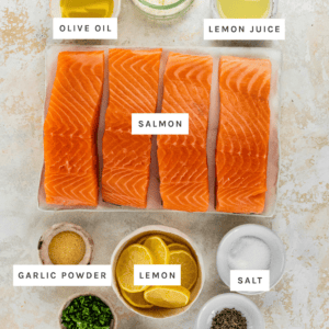 Ingredients measured out to make Parmesan Crusted Salmon: Olive Oil, Lemon Juice, Garlic Powder, Parsley, Basil, Pepper, Salt, Salmon, Lemons, Parmesan Cheese
