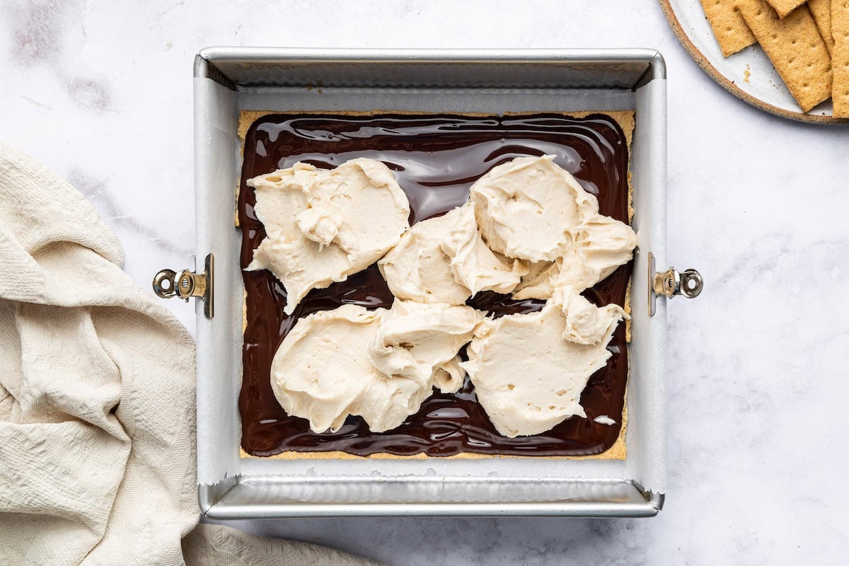 Dollops of whipped protein filling on top of a chocolate layer in a baking dish.