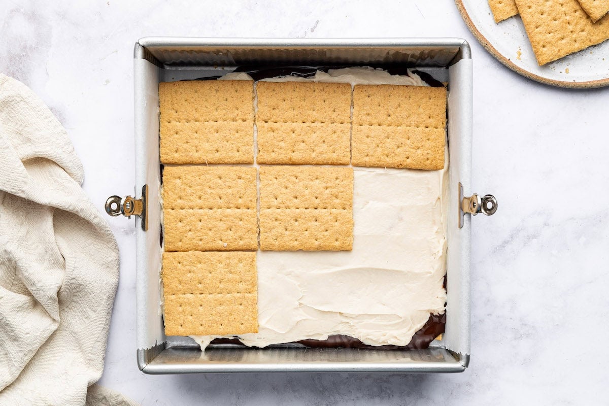 Graham crackers layered over whipped protein filling in a square baking dish.