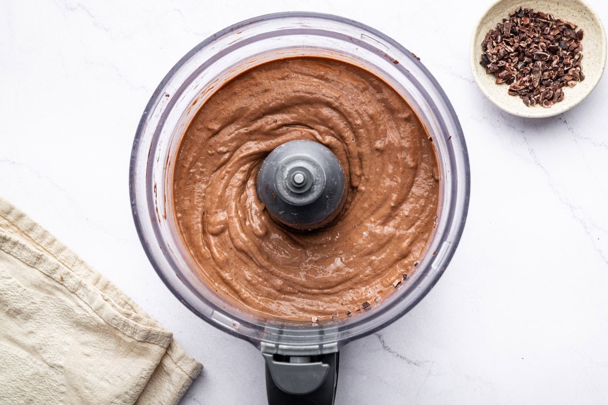 Smooth, blended chocolate protein ice cream mixture in a food processor.