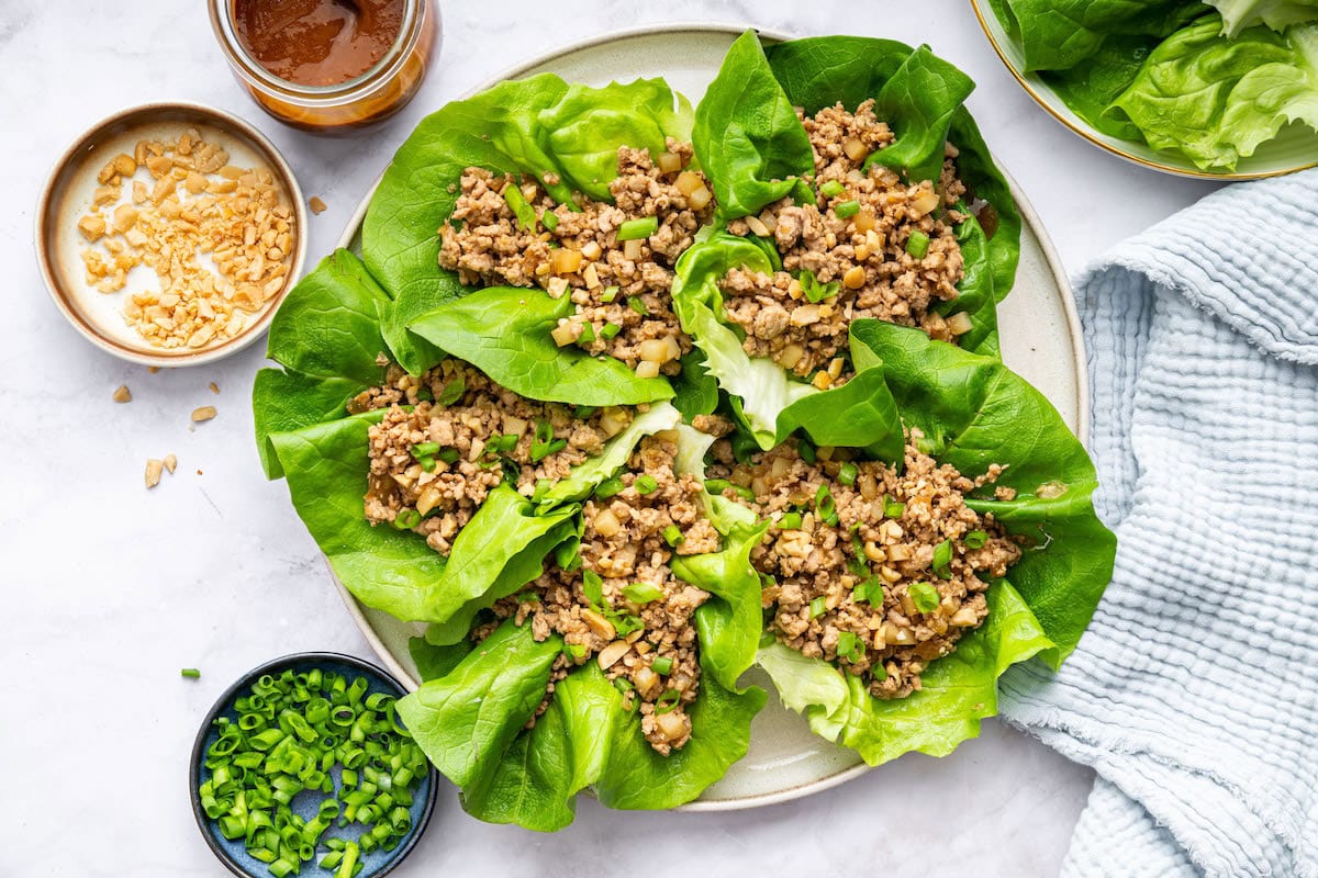 Ground chicken lettuce wraps served on a plate with fresh green onions.