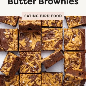 Peanut butter brownies cut into 16 squares, arranged on a white surface. Some pieces are stacked or slightly tilted.