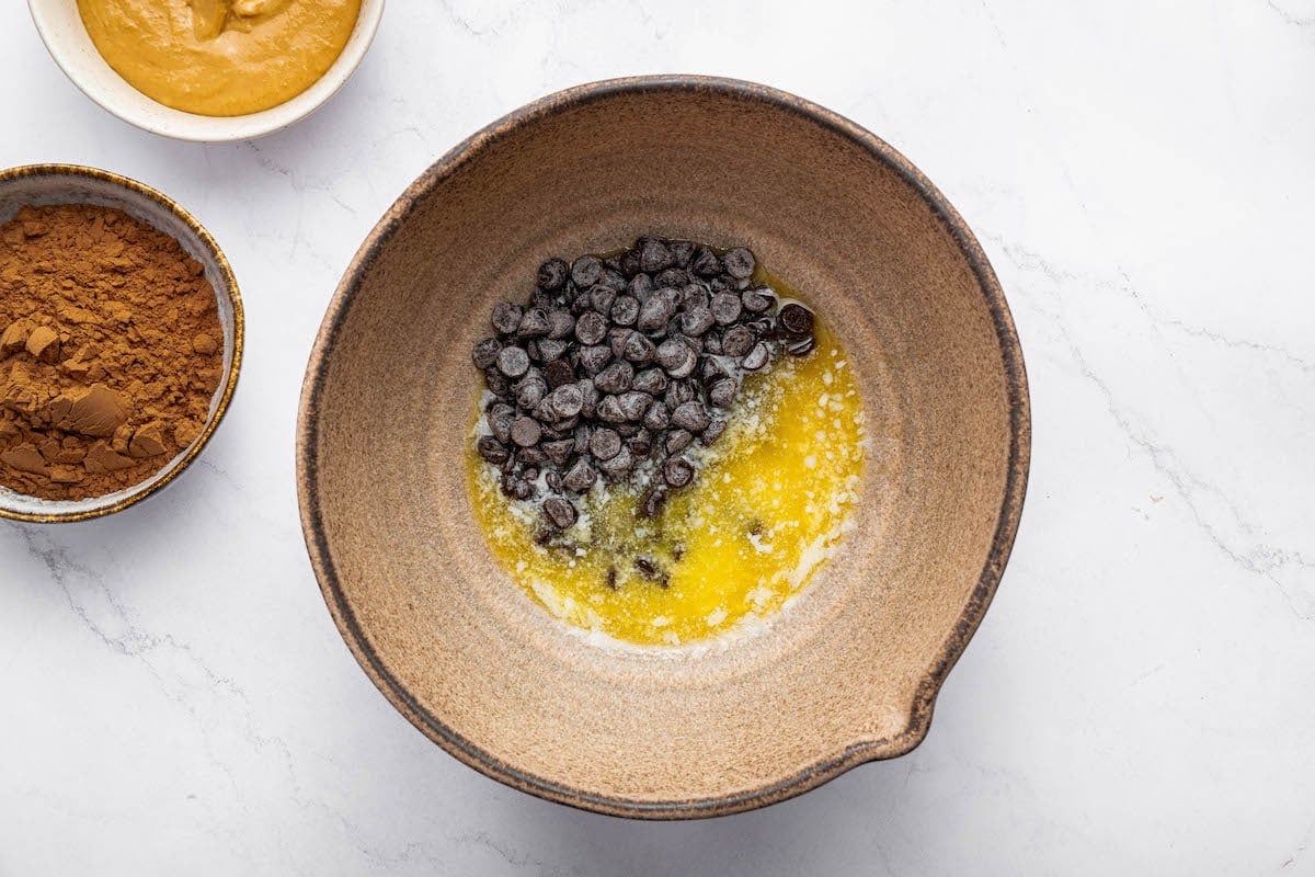 Chocolate chip and melted butter in a mixing bowl before being melted together.