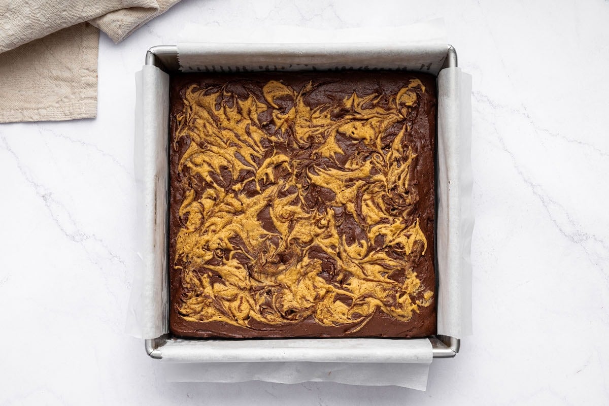 Baked peanut butter brownies in a square baking dish that's lined with parchment paper.