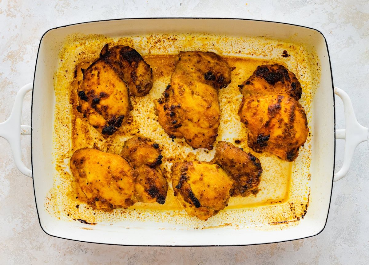 Five chicken chicken thighs in a baking dish right after being baked in the oven.