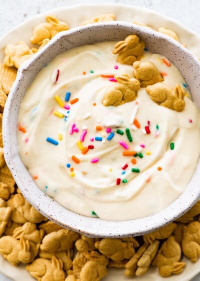 Protein Dunkaroo dip in a white bowl with four bunny crackers in the dip and more bunny crackers on the side.