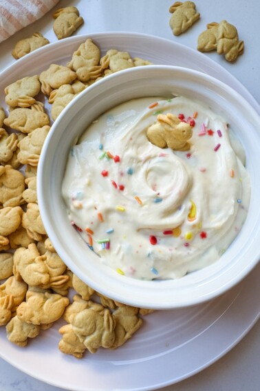 Protein Dunkaroo dip in a white bowl with bunny crackers on the side.