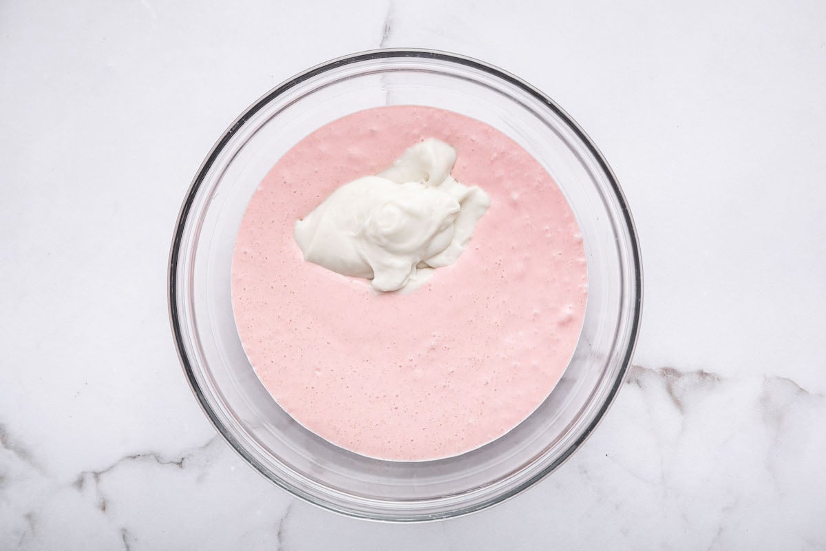The blended strawberry cottage cheese mixture in a glass bowl with the cocowhip added to it.