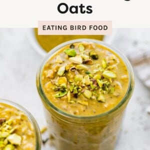 Glass jar filled with high protein pistachio overnight oats topped with chopped pistachios, surrounded by other jars