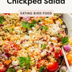 Colorful quinoa chickpea salad in a white bowl, mixed with fresh veggies, feta, and parsley,