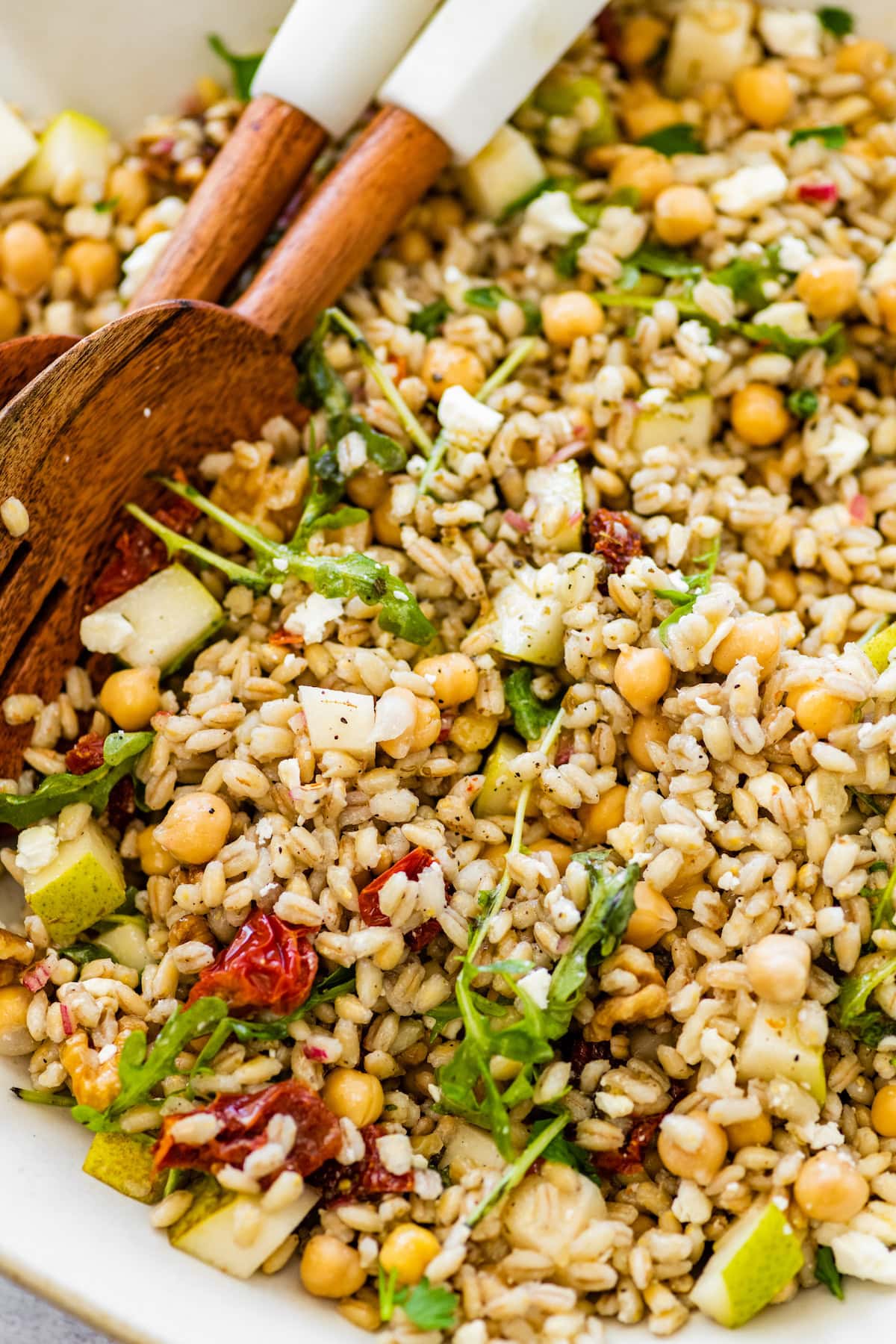 Barley salad showing grains tossed with chickpeas, arugula, sun-dried tomatoes, walnuts, pear, and crumbled feta.