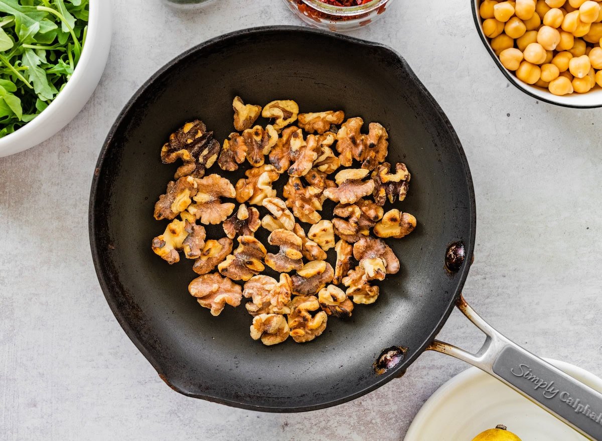 A black skillet filled with toasted walnuts.